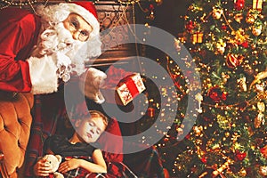 Santa Claus presents Christmas gift to sleeping child girl in Ch