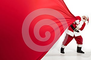 Santa Claus pulling huge bag full of christmas presents isolated on white background