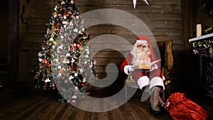 Santa Claus pulling out reading book near christmas tree at home