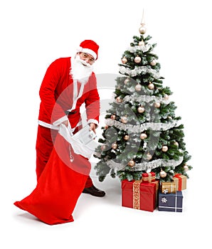 Santa Claus putting gifts under christmas tree