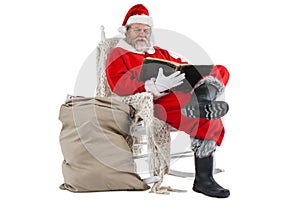 Santa claus reading bible with sack of christmas present beside him
