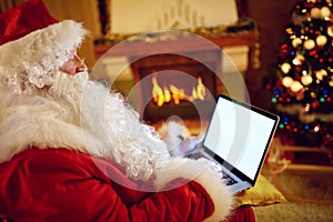 Santa Claus reading email on laptop with Christmas requesting