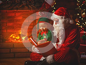Santa claus reads a book to a little elf by Christmas tree