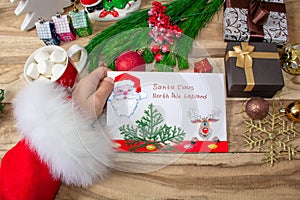 Santa Claus received a letter and holds it in his hands at the North Pole in Lapland, male hands on a wooden background with decor