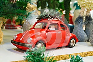 Santa Claus in a red car carries a Christmas tree on the roof of the car.