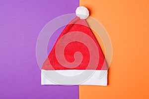 Santa Claus red hat on orange and wiolet paper background , minimal style.