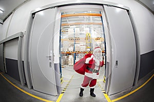 Santa Claus + red sack leaving storehouse of gifts photo