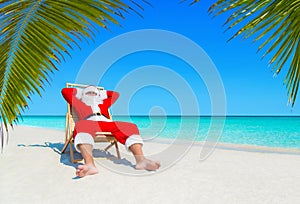 Santa Claus relax in sunlounger at sandy tropical palm beach