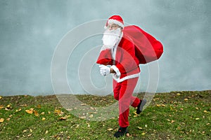 Santa Claus runs with a big red bag with gifts.