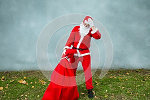 Santa Claus runs with a big red bag with gifts.