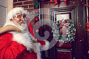 Santa Claus with sack in front of Christmas door