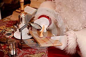 Santa Claus sealing a letter, looking through magnifier glass