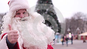 Santa Claus shows his thumb up, looks at the camera and smiles. Smiling Santa shows thumb up.