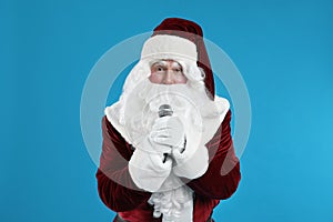 Santa Claus singing with microphone on blue background. Christmas music