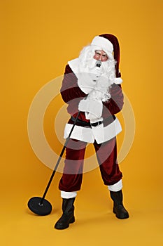 Santa Claus singing with microphone on yellow background. Christmas music