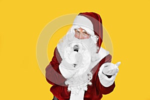 Santa Claus singing with microphone on yellow background. Christmas music