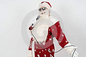 Santa Claus sings with a microphone in his hand. Isolated on white