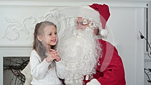 Santa Claus sitting in a chair with a little girl dreaming about her Christmas presents