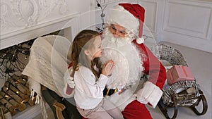 Santa Claus sitting in a chair with a little girl dreaming about her Christmas presents