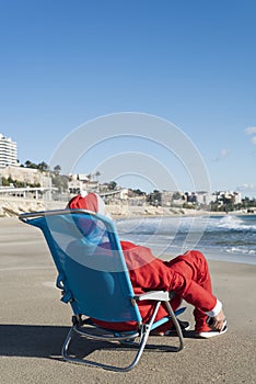 Santa claus sitting in a deckchair on the beach