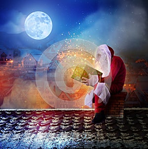 Santa Claus sitting on the roof holdig a gift in his hands