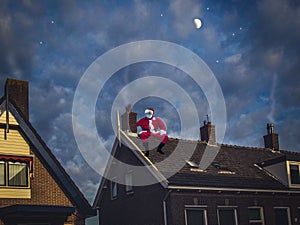 Santa Claus sitting on the roof of a house in the night. Merry C