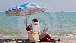 Santa Claus sitting under an beach umbrella at sea on a hot summer day