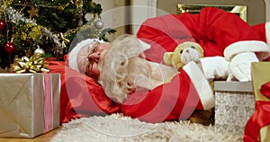 Santa claus sleeping with christmas gifts and teddy bear