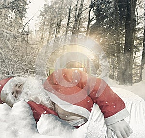 Santa claus sleeping on snow in front of gifts at forest environment