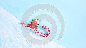 Santa Claus on a sleigh of candy canes, swiftly rushes from under the clouds and along the snowy slope of the mountain. Blue backg