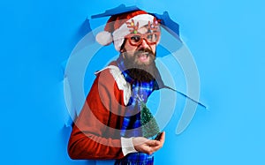 Santa Claus with small Christmas tree looking through paper hole. Discount. New year sales.