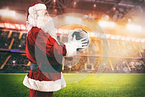 Santa Claus with a soccer ball in his hands inside a soccer stadium