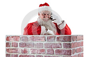 Santa claus standing beside chimney and talking on mobile phone