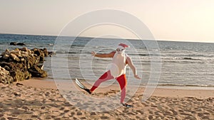 Santa Claus summer vacation. Father Christmas having fun. Funny Santa, in flippers runs through sandy beach to the sea