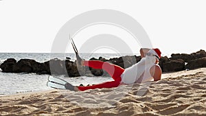 Santa Claus summer vacation. Santa Claus having fun. Funny Santa, in flippers, relaxing while lying on sandy beach by