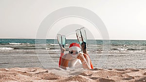 Santa Claus summer vacation. Santa Claus having fun. Funny Santa, in flippers, relaxing while lying on sandy beach by