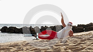 Santa Claus summer vacation. Santa Claus having fun. Funny Santa, in flippers, relaxing while lying on sandy beach by