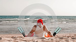 Santa Claus summer vacation. Santa Claus having fun. Funny Santa, in flippers, relaxing while sitting on sandy beach by