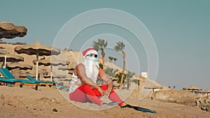 Santa Claus summer vacation. Santa Claus having fun. Funny Santa, in protective mask, sunglasses and flippers, relaxing