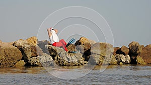 Santa Claus sunbathes. Santa Claus having fun. Funny Santa, in sunglasses and flippers sitting on rocky beach by the sea