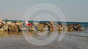 Santa Claus sunbathes. Santa Claus having fun. Funny Santa, in sunglasses and flippers sitting on rocky beach by the sea