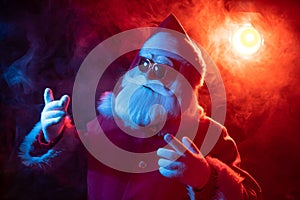 Santa claus in sunglasses in red-blue smoke. Party for Christmas.