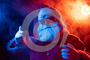 Santa claus in sunglasses in red-blue smoke. Party for Christmas.