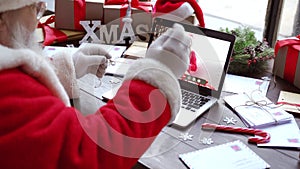 Santa Claus talking to child on laptop video call open present sit at table.