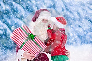 Santa Claus talking to little girl in snowy park