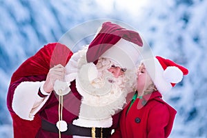 Santa Claus talking to little girl in snowy park