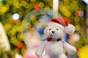 Santa claus teddy bear wearing hat sitting in front of colorful bokeh lights