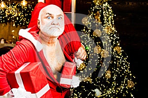 Santa Claus thief with a bag of christmas gifts. Home Burglar Santa Claus in a Mask Into the House. Best prices for