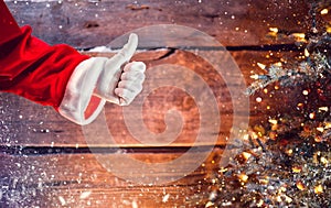 Santa Claus thumb up gesture over Christmas wooden background