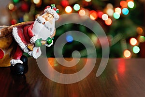 Santa Claus toy brings Christmas tree at blue snowy night bokeh
